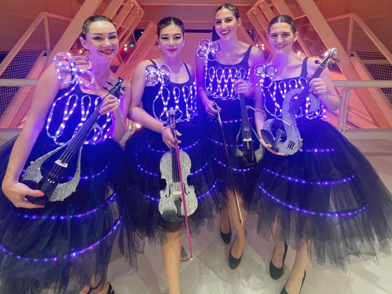 Quatuor de violonistes LED, violonistes led, violonistes lumineuses, spectacle son et lumière, domaine viticole, dîner royal, festival Som’Art, musique classique moderne, violons électriques, costumes LED, expérience sensorielle, art et sommellerie.