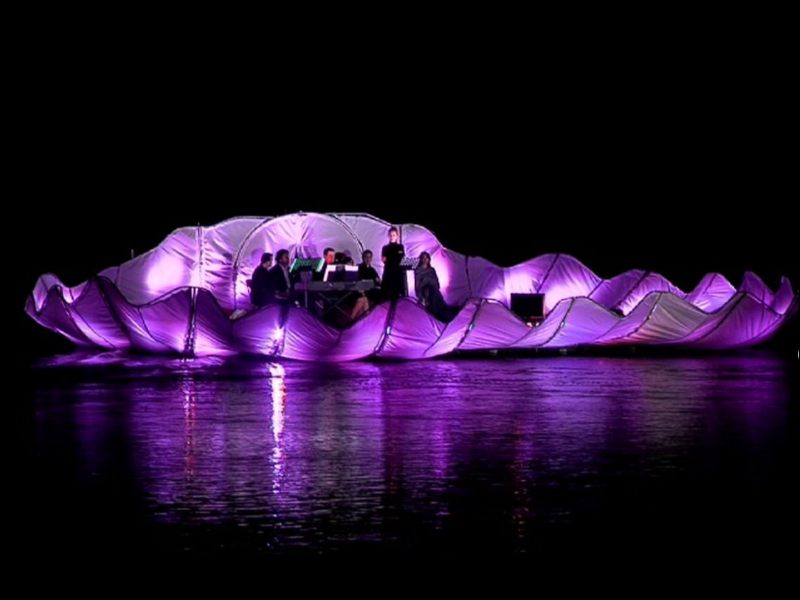 scène flottante, scène coquillage, performance aquatique, scène flottante artistique, concert en plein air, performance nature, scène illuminée, scène panoramique, festival flottant, spectacle aquatique